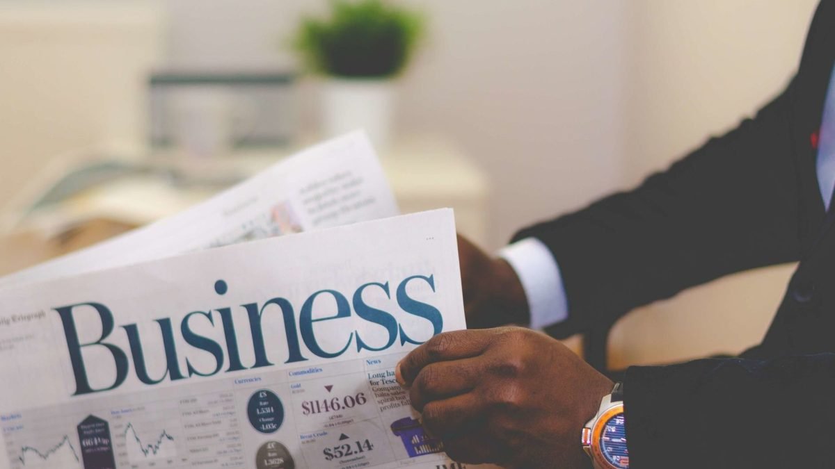 Close-up of a businessman reading a newspaper indoors, focusing on business headlines. — Cultivating Creativity One Note at a