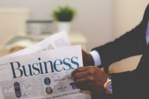 Close-up of a businessman reading a newspaper indoors, focusing on business headlines. — Cultivating Creativity One Note at a
