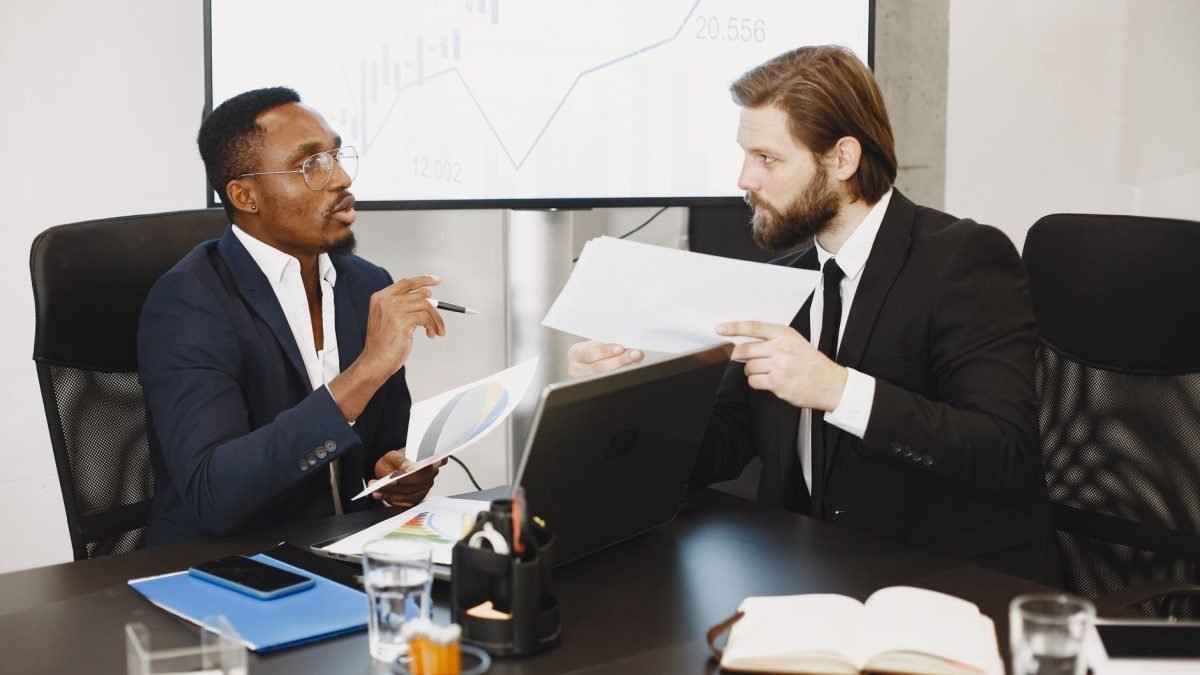 Two business professionals engaged in a planning meeting, discussing documents in a modern office setting. — Decoding the Fin