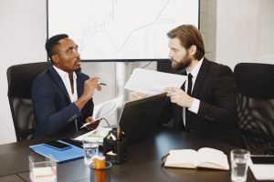 Two business professionals engaged in a planning meeting, discussing documents in a modern office setting. — Decoding the Fin