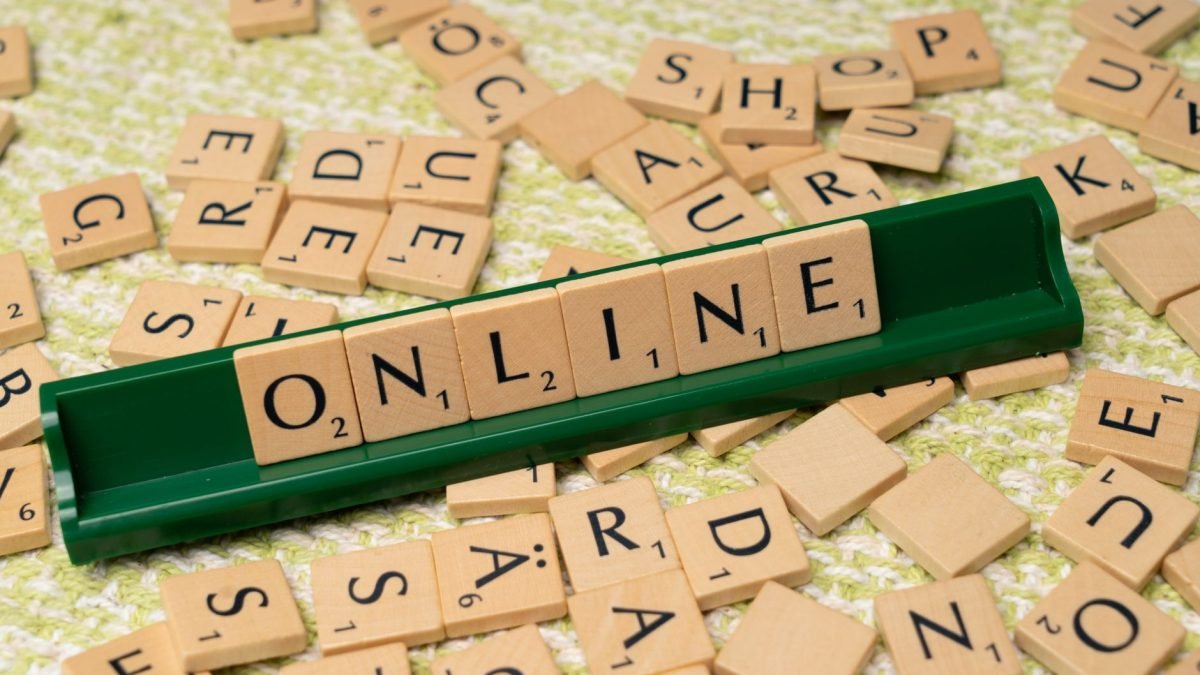 Scrabble tiles spelling 'online' on a green tray amidst scattered tiles, symbolizing digital connectivity and language. — Exp