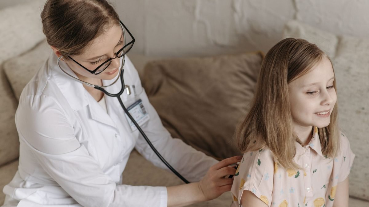 A doctor with a stethoscope examining a smiling girl during a medical check-up at home. — Make Informed Decisions About TRT C