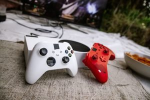 White and red wireless gaming controllers on a textured surface near chips and a TV screen. — No Deposit Casinos Reward You B