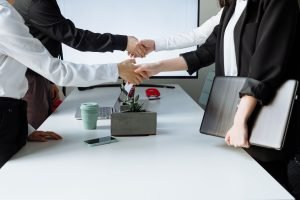 Professionals sealing a deal with a handshake across a conference table during a business meeting. — Revolutionizing Recovery