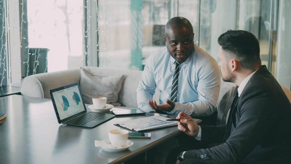 Two business professionals engaged in discussion over laptops and documents. — Top Construction Management Apps to Improve Te